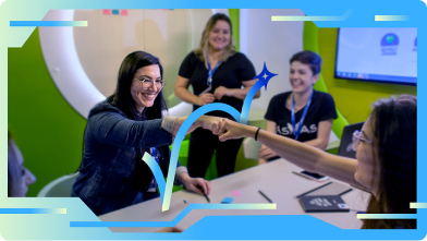 foto de grupo de mulheres com características diversas. Duas delas sorriem e fazem "high five" com as mãos.